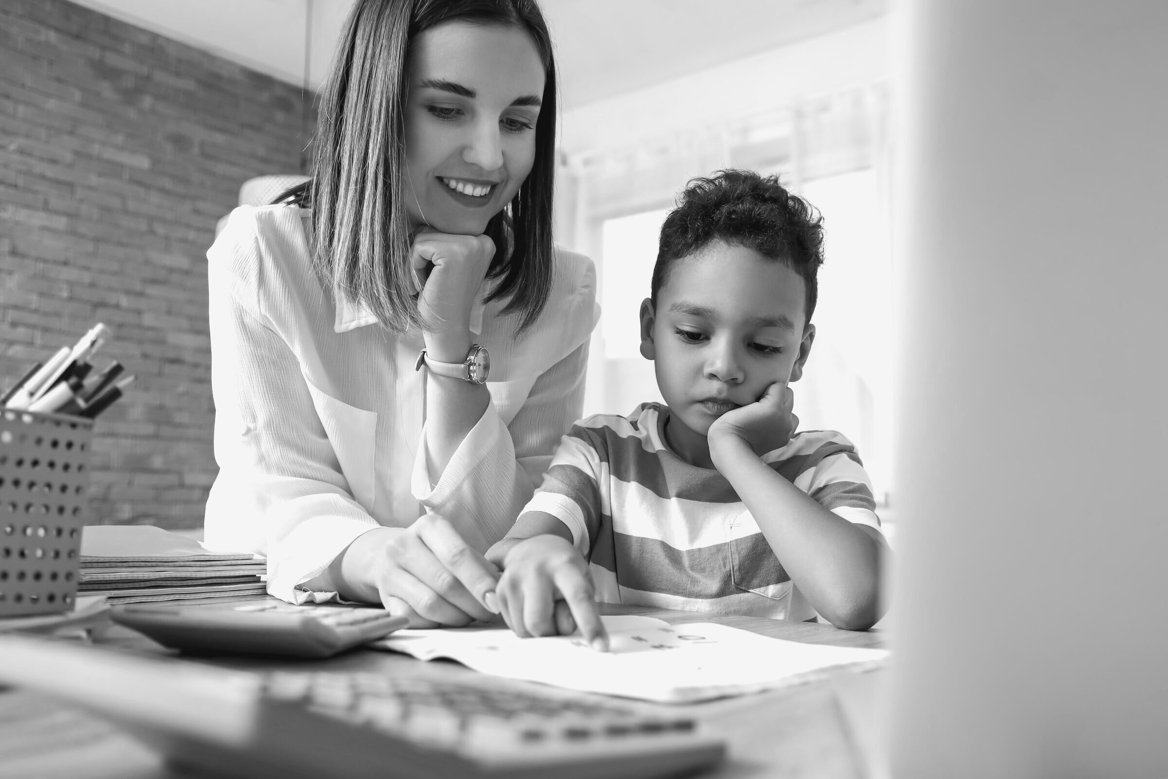 A tutor points to a page while working one-to-one with a child